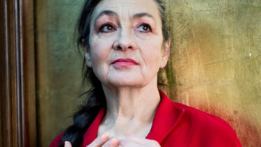 Femme en gros plan le regard fuyant, habillée d'un haut rouge et coiffée d'une tresse