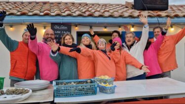 groupe de personnes vêtues de vareuses colorées devant une cabane ostréicole