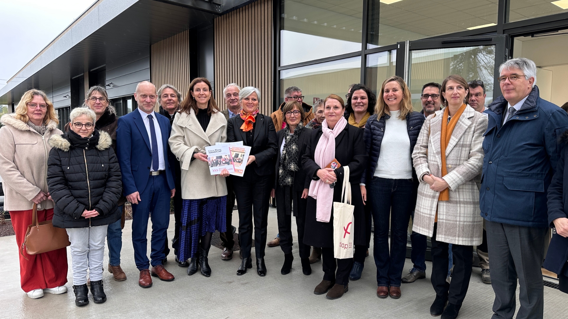 une dizaine de personnes qui posent en ligne devant un bâtiment en arrière plan