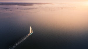Un bateau qui prend le large dans un ciel rosé de fin de journée