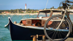 Vélo devant une pinasse avec un arrière plan le Phare du Cap Ferret