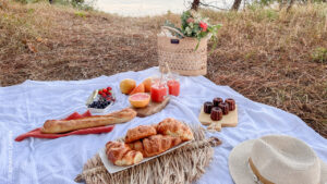 Pique nique sucré avec des jus de fruit, canelés, viennoiserie et un panier en fond