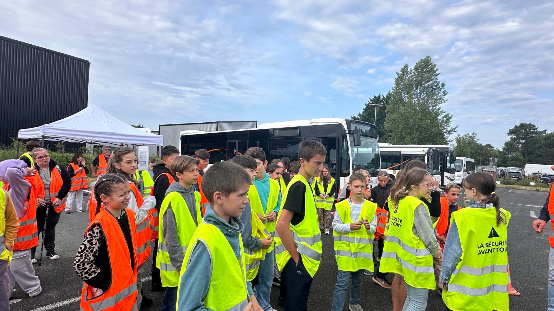 jeunes enfants qui portent des gilets fluorescents devant un bus