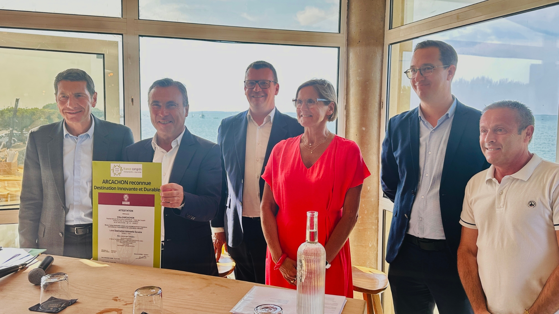 1 femme et 5 hommes en rang qui posent devant l'objectif. Yves Foulon, maire d'Arcachon tient une pancarte correspondant au label destination innovante et durable