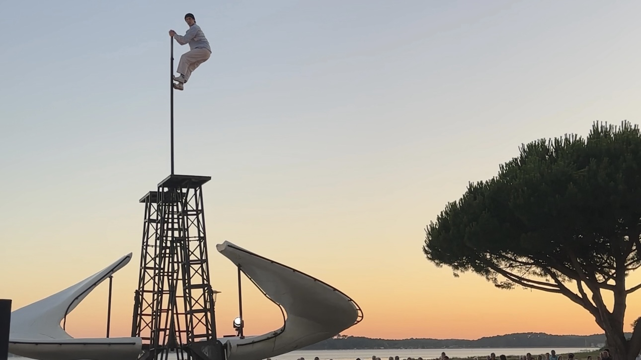 Un acrobate en haut d'un mat au coucher du soleil