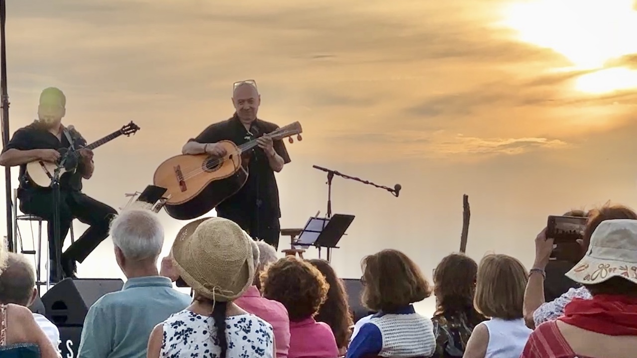Guitariste face au public au coucher du soleil