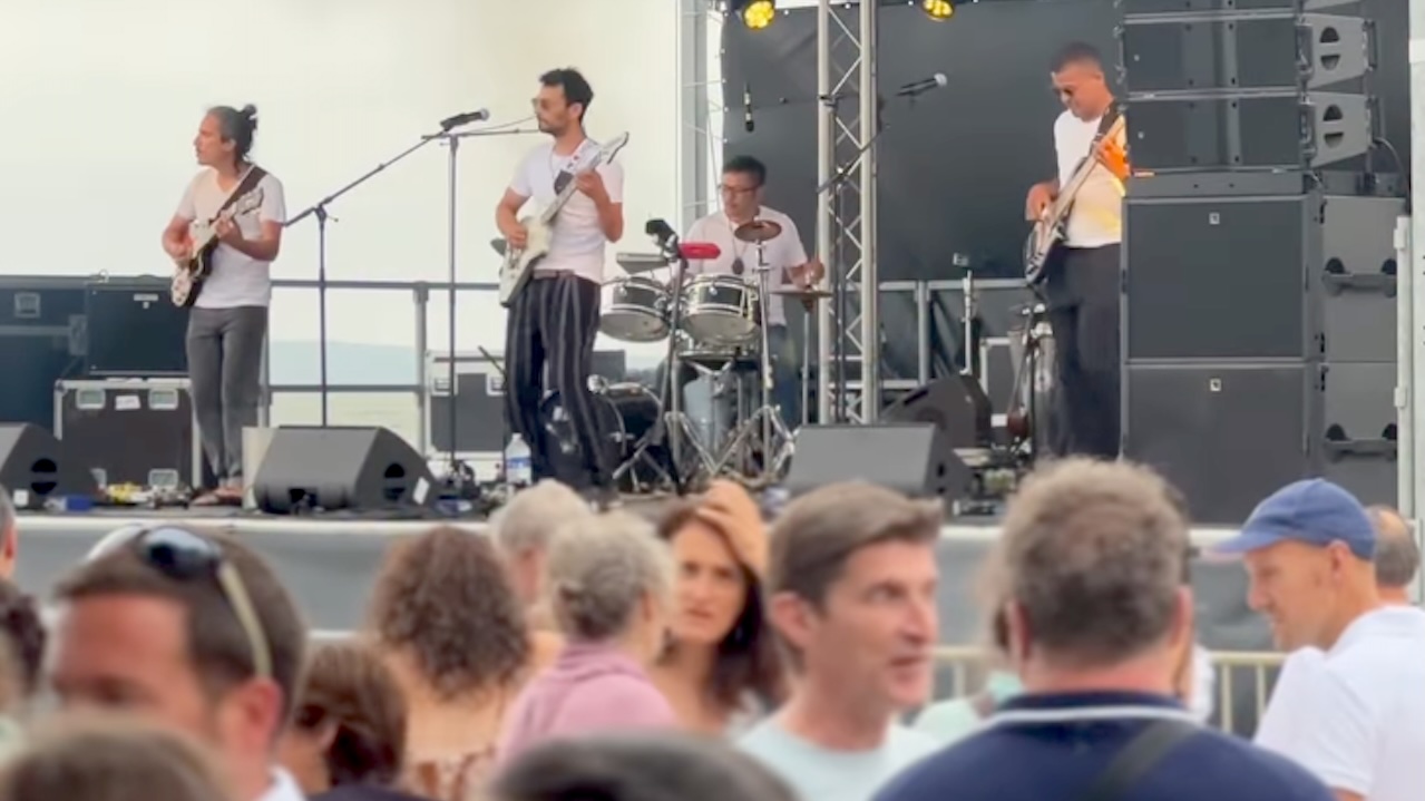 Des musiciens en noir et blanc sur scène devant un public nombreux