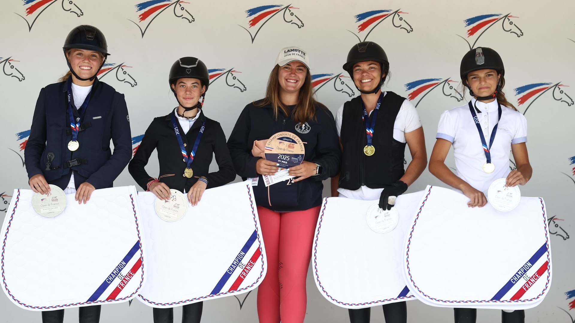 5 jeunes femmes en tenue d'équitation avec des tapis dans les mains et des médailles autour du coup. 4 cavalières du centre équestre d'andernos au championnat de france d'équitation