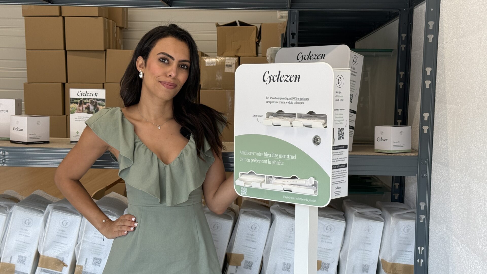 Une femme devant un distributeur de protections hygiéniques