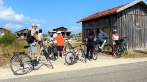 Visite Office : Vélostréïtour Gujan-Mestras - Les visiteurs et leurs vélos au Port de Gujan-Mestras en observation des cabanes ostréicoles