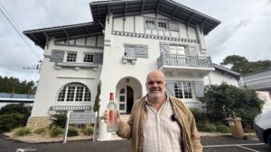 Un homme tient uje bouteille devant le bâtiment historique des Abatilles