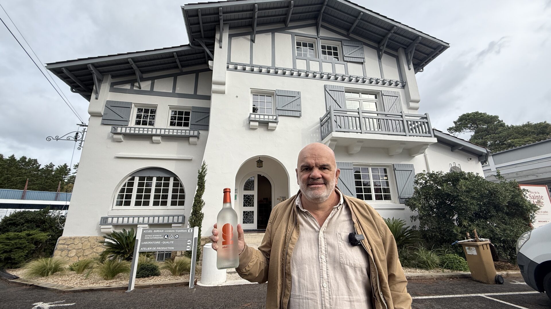 Un homme tient uje bouteille devant le bâtiment historique des Abatilles