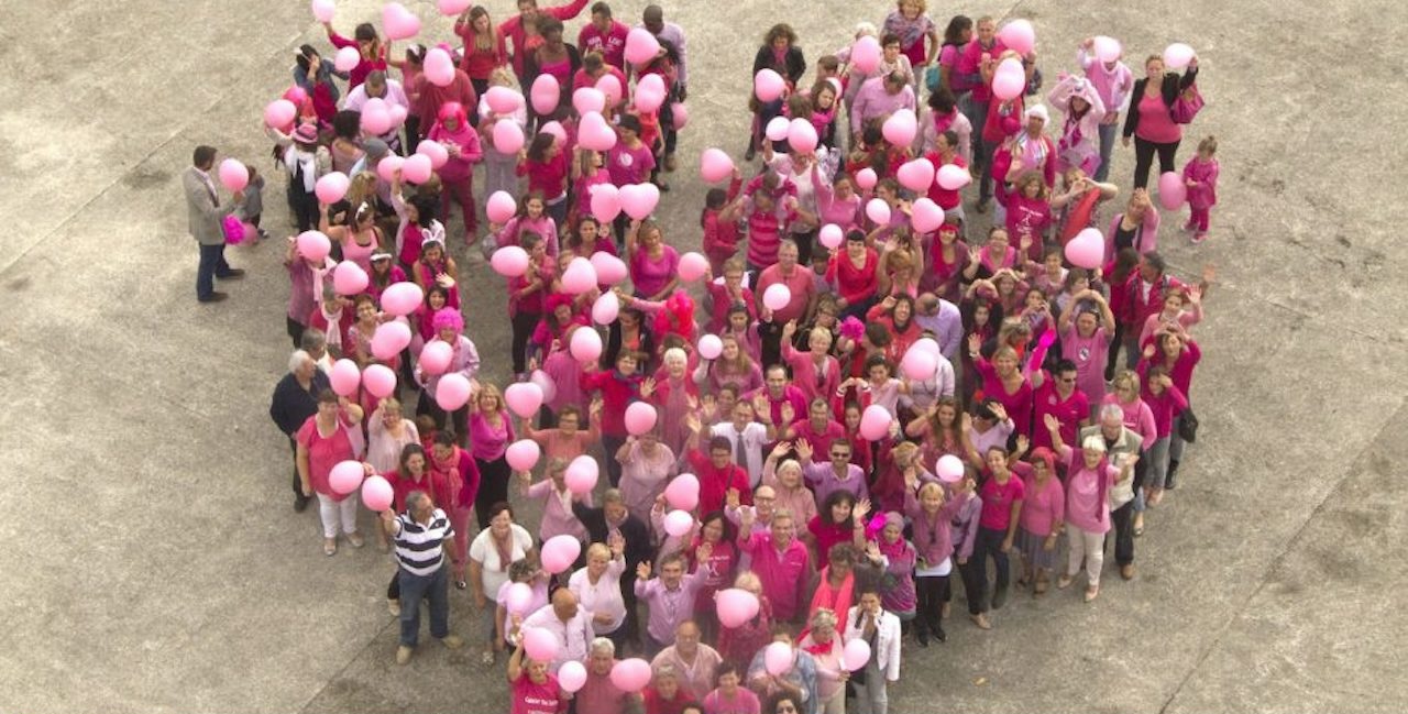 Un groupe de personnes en teeshirt rose forment un coeur vu du ciel