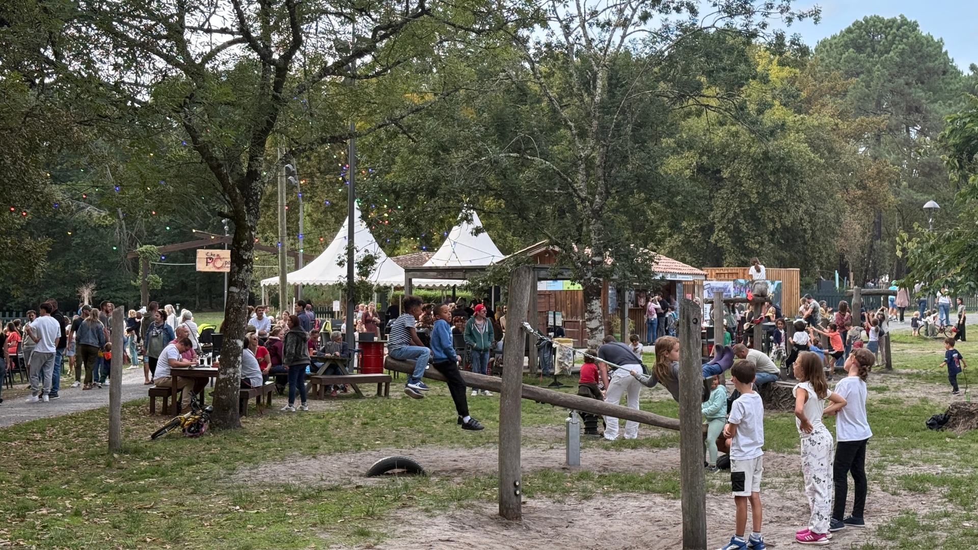 des enfants au premier plan qui jouent et des adultes à la guinguette de mios à l'occasion de la fête du parc birabeille
