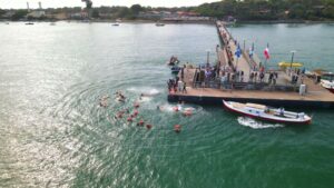 Un groupe de nageurs à l'eau devant une jetée