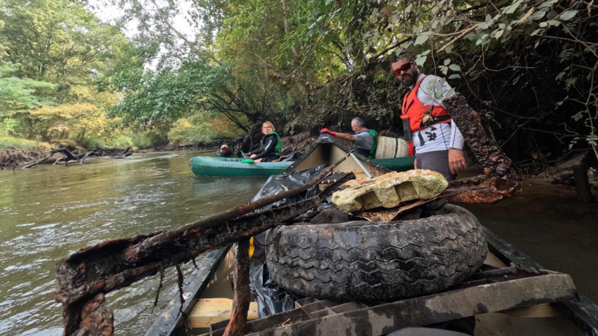 sur la leyre, un canoe au premier plan rempli de déchets avec des bénévoles autour et dans un deuxième canoë