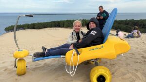opération handi dune : un homme en situation de hancap dans un tiralo au sommet de la dune du pilat avec sa femme à côté de lui