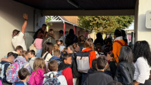 des jeunes élèves qui entrent dans l'enceinte de l'école Jules Ferry de Biganos lors de la rentrée scolaire 2025 avec des sacs sur le dos.