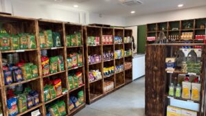 intérieur de l'épicerie sociale et solidaire de Biganos au sein de la maison solidaire : des étagères en bois fumé et des produits alimentaires dessus