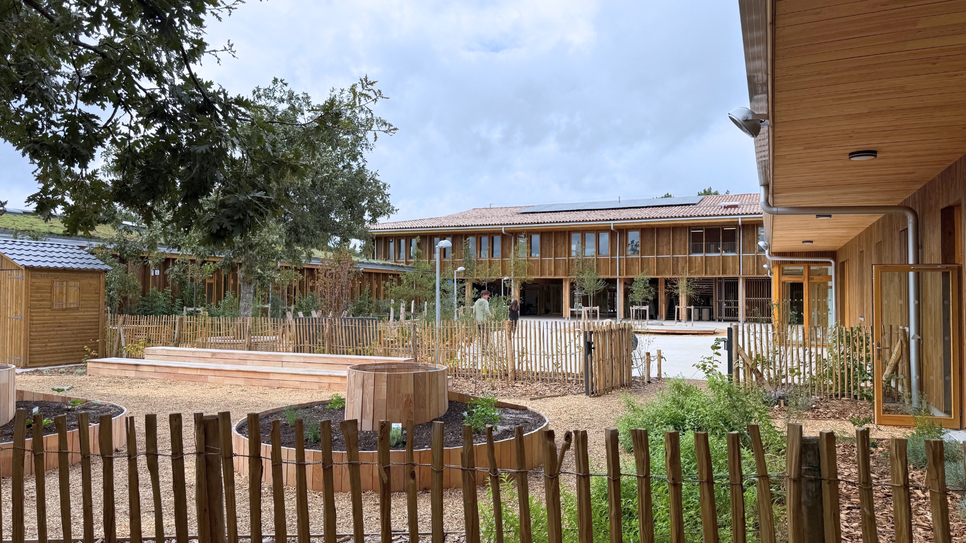 nouvelle école d'audenge : batiments en bois, sol clair et végétation