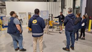 des facteurs de dos dans un entrepot avec un chien au sol