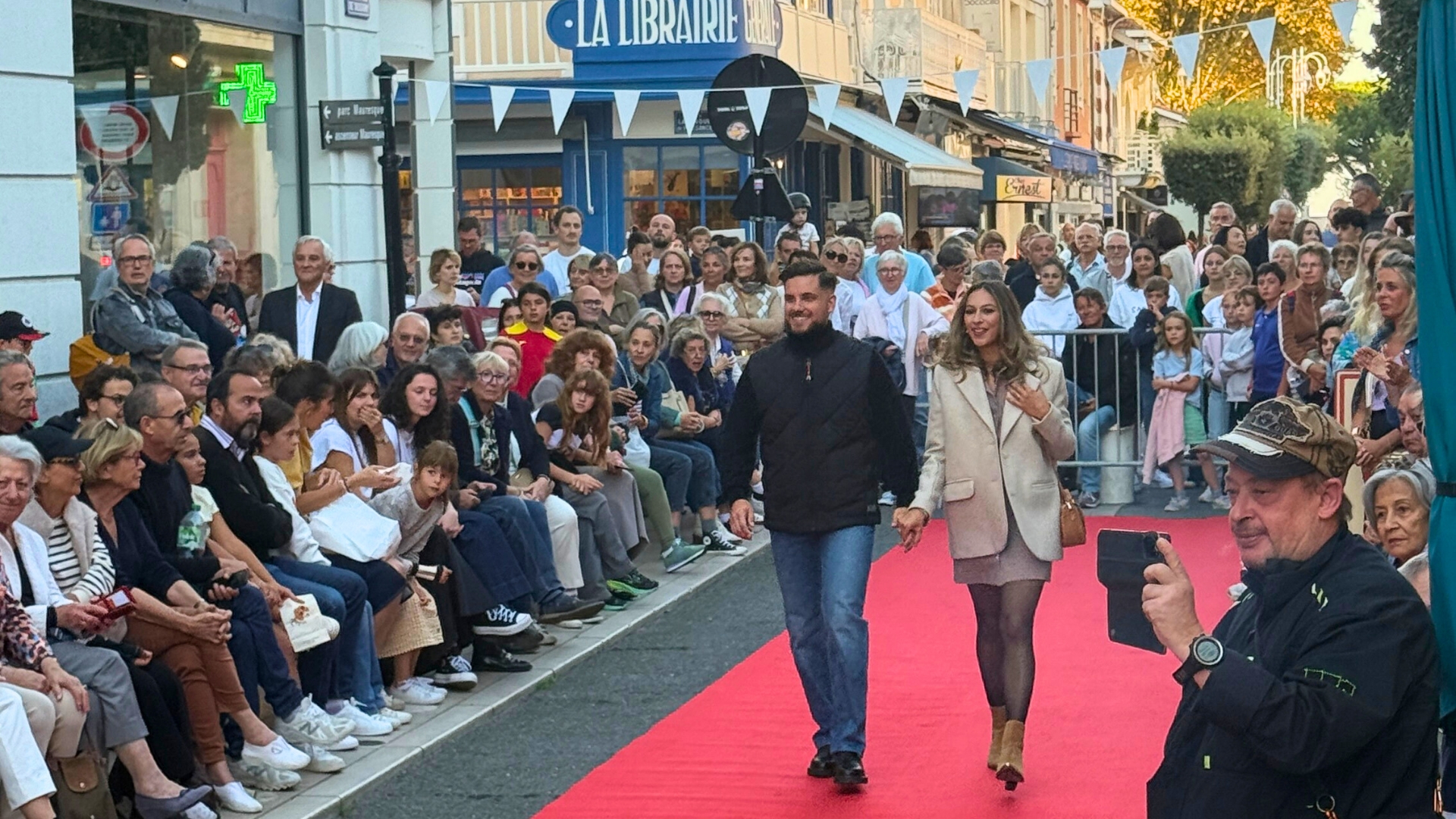 un couple qui défile sur un tapis rouge avec des spectateurs de part et d'autre pour le défilé d'Arcachon Bonjour