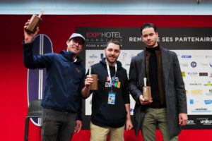 trois hommes présente leur trophée devant un fond rouge