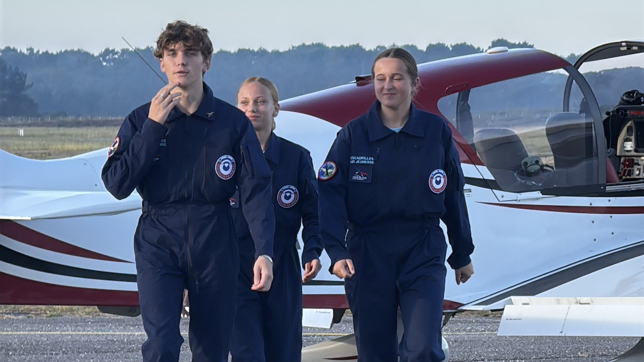 3 jeunes en uniformes bleu-marines devant un avion