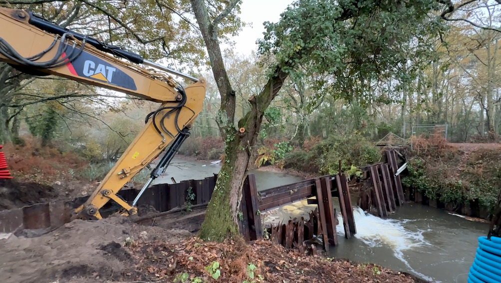 tractopelle u bord d'un cour d'eau