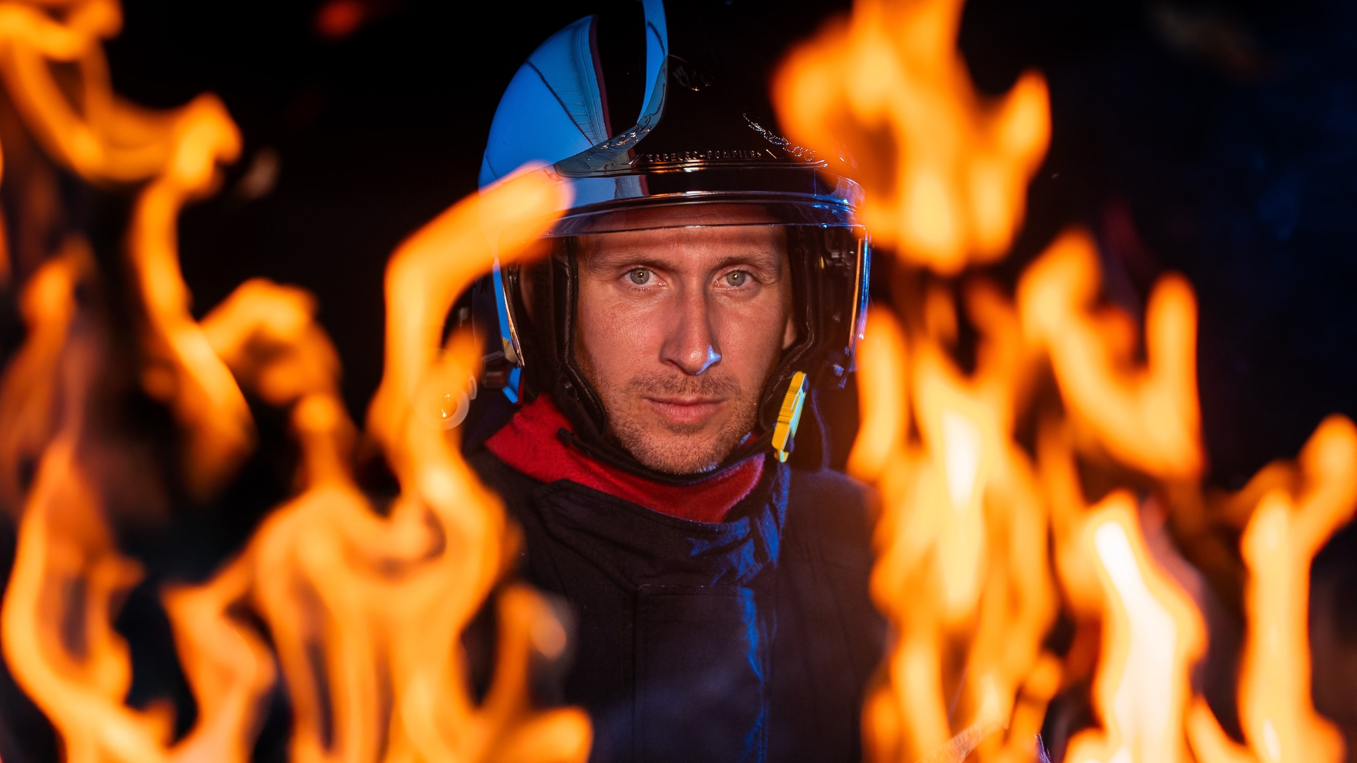 un pompier en tenue avec un casque au milieu des flammes