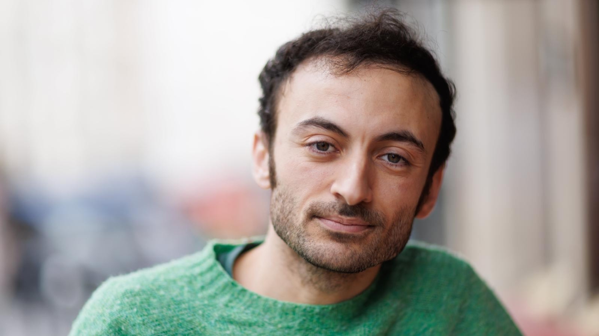 portrait de Soufiane Khaloua : homme brun et barbu, face à l'objectif, avec un pull vert