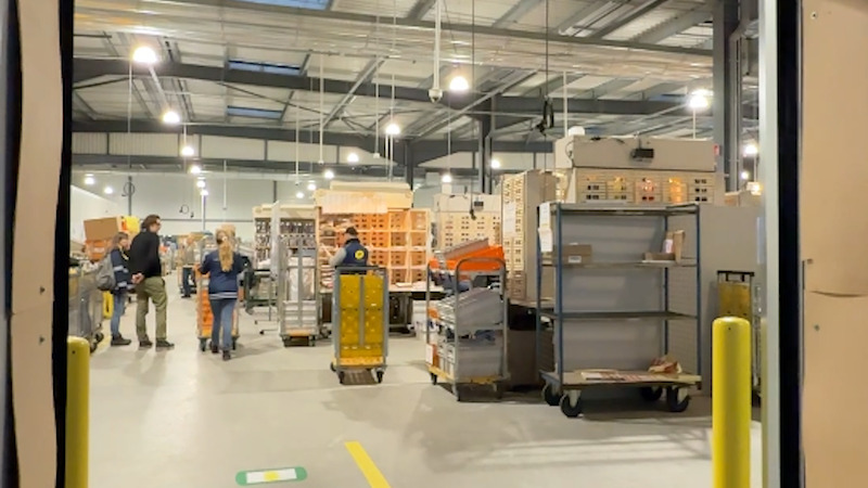 un entreot ouvert. Dedans, des chariots et bacs rempli de colis et de lettres