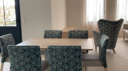 salle à manger avec chaises bleues et tbles en bois devant une fenetre.