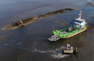 bateau technique vert à côté d'un parc ostreicole
