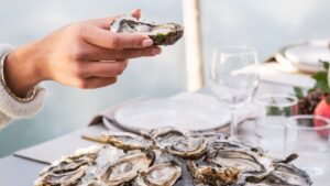 plateau d'huitres, au-dessus : une main tient une huitre