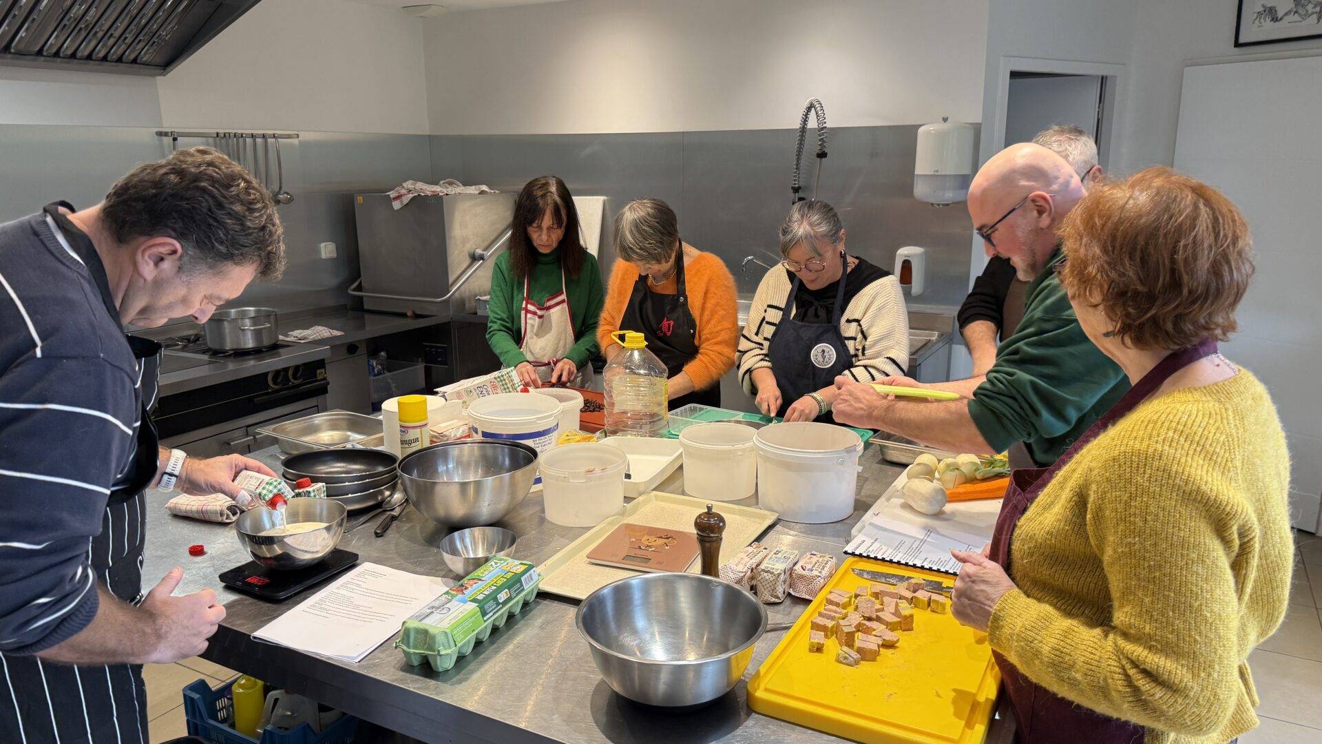 Les participants à un cours de cuisine rassemblés autour du plan de travail