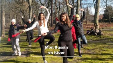 deux jeunes femmes au premier plan en train d'effectuer une posture de dao yin. Elles tiennent des éventail dans la main. Elles sont dans une chênaie avec d'autres participants en arrière plan