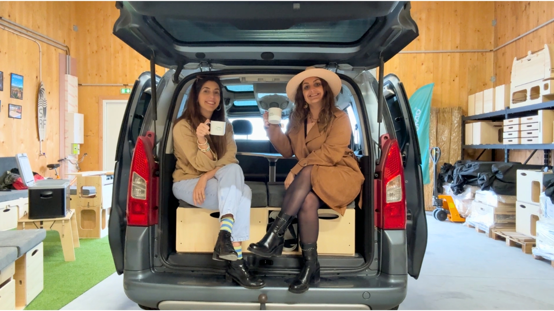 deux jeunes femmes souriantes dans le coffre d'un citroen berlingo qui contient un kit d'aménagement en van de la société tchao tchao
