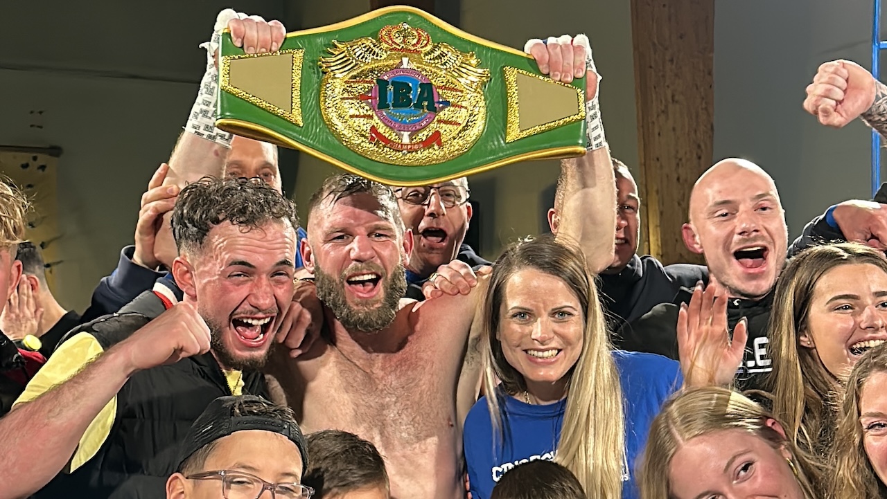 Un homme tient un bouclier de boxe dans les mains. il est entouré d'une foule de personne