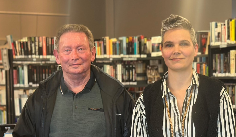 un homme et une femme pose devant des rayonages de livres