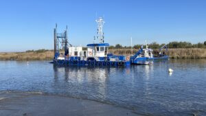 bateau bleu et blanc, drage du Siba dans la Leyre avec du sable découvert au premier plan et la végétation en arrière plan