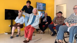 des seniors assis en train de jouer à des jeux video, avec des manettes en main.