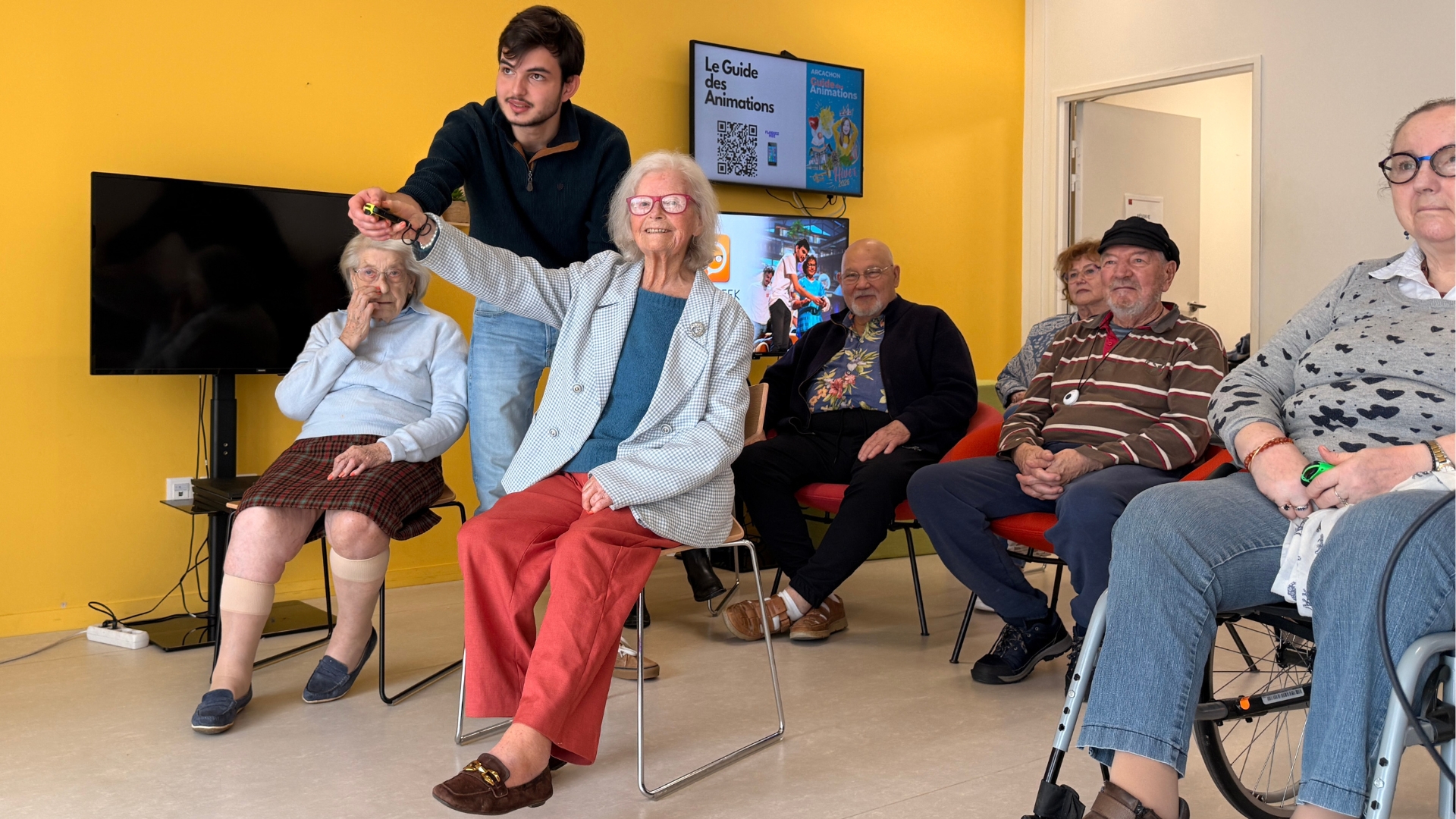 des seniors assis en train de jouer à des jeux video, avec des manettes en main.