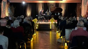 Concert de piano. Des chandelles sont disposées dans l'allée du public