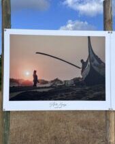 photographie issue des banales photographiques d'arès. une personne devant la coque d'un bateau au coucher de soleil