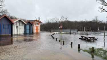 inondation. Des cabanes colorées sont entourées d'eau. Une table de pique-nique est submergées.