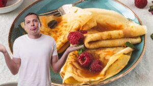 jeune homme l'air interrogé au premier plan avec des crêpes pendant la chandeleur en arrière plan