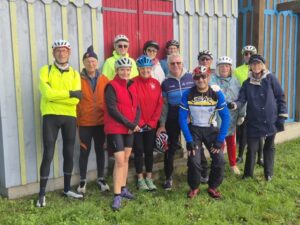 Groupe de sportifs retraités devant une cabane en bois colorée