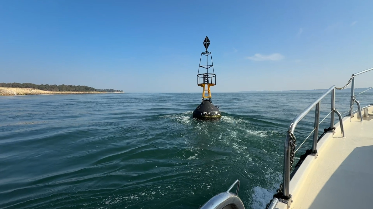 balise maritime devant un bateau. dans le fond en arrière plan une langue terre sableuse