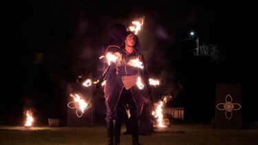 sur le stade de gujan, la nuit; 2 personnes qui font un spectacle pyrotechnique en tenant des torches enflammées pour le carnaval 2026